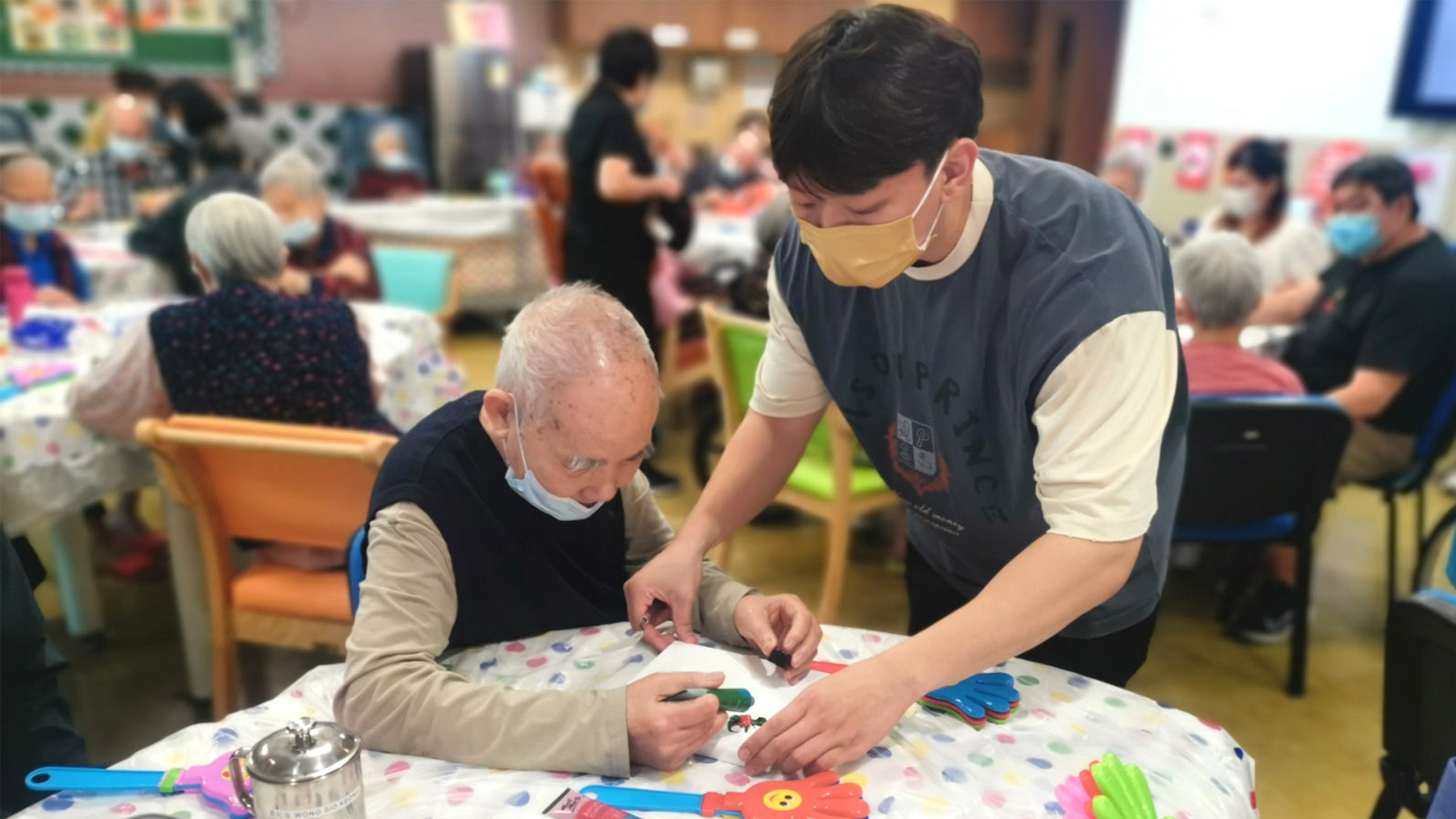 dementia friendly Younger man helps an older gentleman in a dementia friendly activity setting